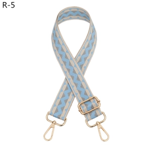 Detail view of adjustable wide bag strap with blue wave pattern and gold metal hooks