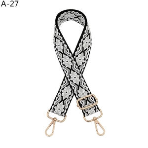 Detail of adjustable black and white geometric jacquard bag strap with gold metal hooks