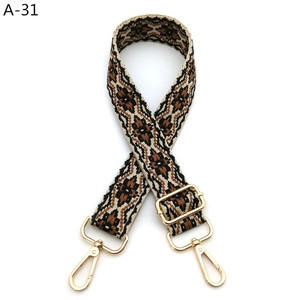 Detail of bohemian geometric woven bag strap with golden metal swivel hooks and buckles