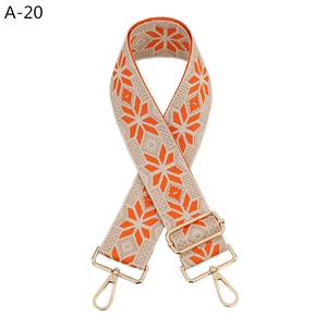 Detalle de correa jacquard ajustable para bolso con patrón geométrico de copos naranja