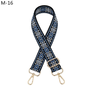 Close-up of ethnic style woven bag strap with blue geometric patterns and gold metal hooks