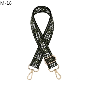 Close-up of ethnic woven shoulder strap with green geometric patterns and gold clips