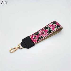 Close-up of floral embroidered bag strap with ethnic patterns and gold metal lobster clasp
