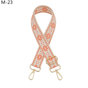Detail of adjustable wide canvas shoulder strap with orange ethnic embroidery and gold metal clips