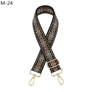 Detail of geometric pattern woven bag strap with golden metal lobster clasps and sliders