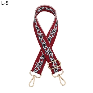 Detail of adjustable wine red woven strap with geometric chain patterns and gold buckles