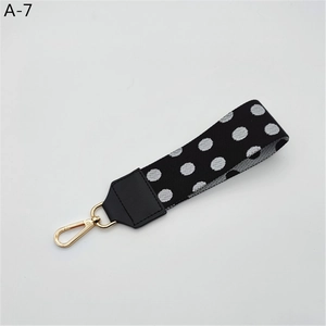 Close-up of a black and white polka dot wrist strap with a premium gold metal lobster clasp