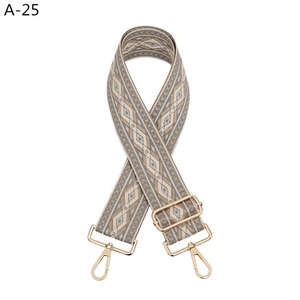 Detail view of ethnic style wide strap with beige geometric weave and gold metal hooks