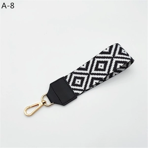 Detail of black and white geometric woven strap with golden metal spring hook closure