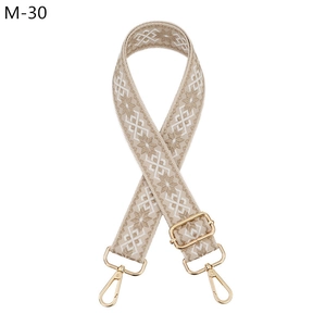 Detail of adjustable geometric jacquard bag strap with gold metal hooks and buckle