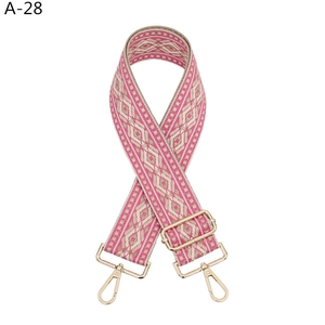 Detail of bohemian pink and gold woven bag strap with adjustable metal buckles