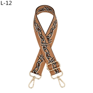 Detail of adjustable brown woven bag strap with geometric patterns and gold metal hooks