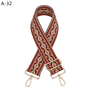 Detail of ethnic embroidered strap with orange geometric patterns and gold metal hooks