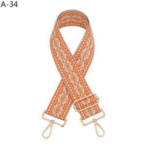 Detail of ethnic geometric embroidery on wide adjustable handbag strap with gold buckles