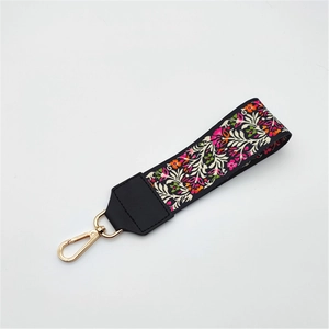 Floral print woven handbag strap with black leather ends and gold lobster clasp buckle