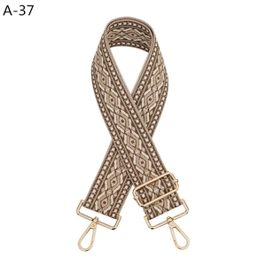 Close-up of geometric ethnic style woven strap with golden metal swivel hooks