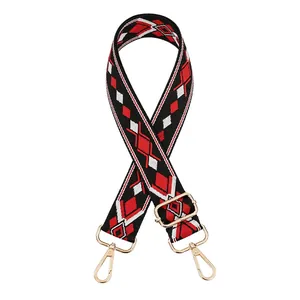 Detail of red and black geometric diamond pattern bag strap with gold metal hooks