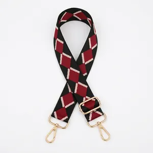 Close-up of red and black diamond pattern bag strap with gold metal buckles and adjuster