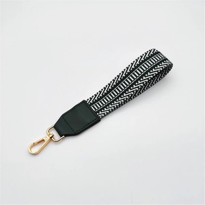 Close-up of geometric woven wrist strap with green leather and gold lobster clasp