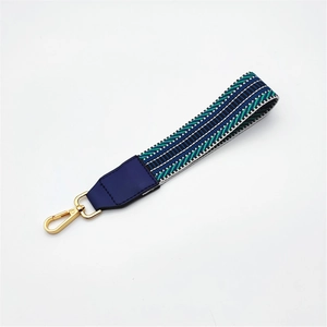 Detail of woven bag strap with blue green wave pattern and golden metal lobster clasp