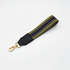 Detail of woven bag strap with yellow black patterns and gold lobster clasp