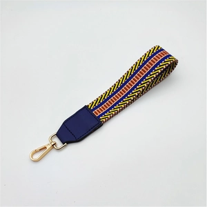Close-up of colorful woven handbag strap with blue leather ends and golden metal clasp