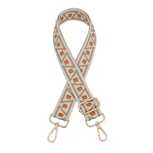 Detail view of woven geometric bag strap with gold metal lobster clasps and buckles