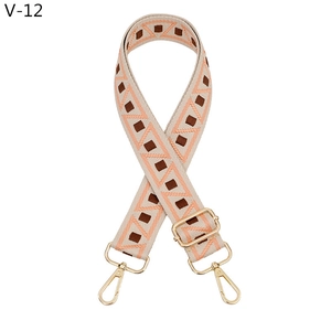 Detail of adjustable woven bag strap with orange geometric patterns and gold metal hooks