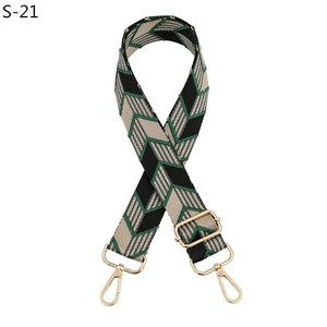 Détail de la bandoulière réglable avec motif en V vert et crochets en métal doré