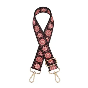 Detail eines Handtaschenriemens mit Vintage-Blumendruck und verstellbaren goldfarbenen Karabinern