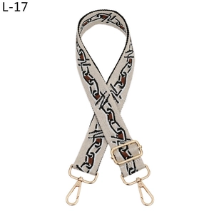 Macro view of adjustable woven shoulder strap with geometric chain pattern and gold hardware