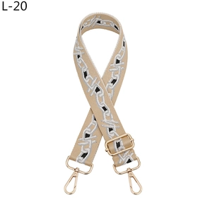 Detail of adjustable beige jacquard purse strap with gold metal hooks and chain pattern