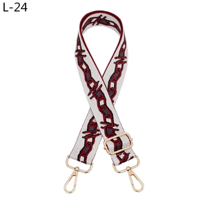 Detail of adjustable cream woven strap with red-black chain pattern and gold buckles