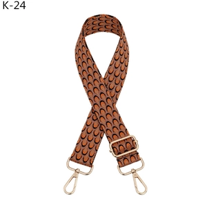 Macro shot of adjustable jacquard bag strap with orange teardrop pattern and gold metal hooks
