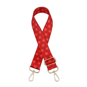 Detail view of red floral patterned bag strap with light gold metal lobster hooks