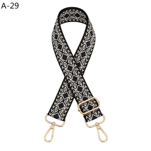 Macro detail of black and white geometric pattern wide strap with gold metal hooks