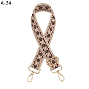 Macro detail of geometric diamond pattern woven strap with gold metal lobster clasps