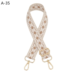 Close-up of geometric jacquard bag strap with golden metal hooks and adjustable buckle