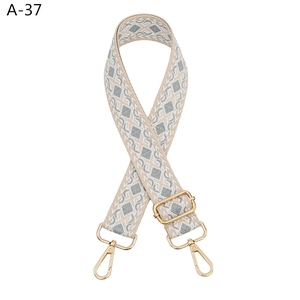 Detail of adjustable gray-blue geometric diamond pattern bag strap with gold metal hooks