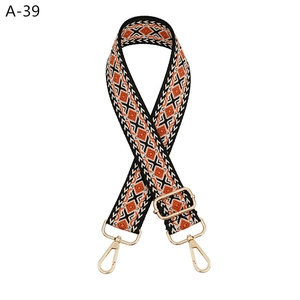 Detail of adjustable geometric weave bag strap with orange diamond pattern and gold hooks