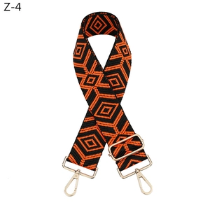 Detail of adjustable orange and black diamond pattern bag strap with gold metal hardware