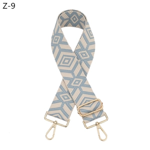Detail of blue and beige geometric diamond pattern wide woven bag strap with gold hardware