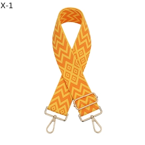 Detail view of jacquard orange geometric bag strap with gold metal lobster clasps