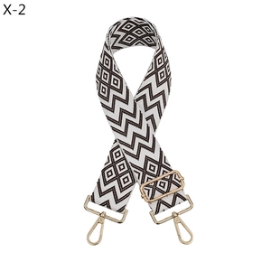 Detail of adjustable black and white geometric jacquard bag strap with gold metal hooks