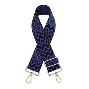 Detail of blue and black geometric diamond jacquard bag strap with gold metal hooks
