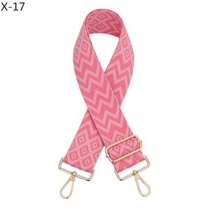 Detail of jacquard woven geometric bag strap in shades of pink with gold metal buckles