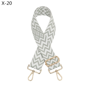 Detail of wide woven bag strap in green and white wave pattern with gold metal clasps