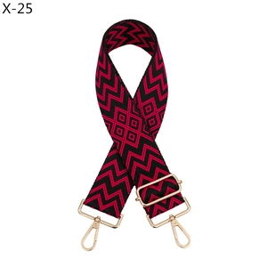 Detail of red and black geometric jacquard bag strap with gold metal hooks and buckle