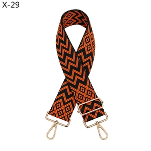 Detail of adjustable geometric jacquard bag strap with gold metal hooks and orange pattern