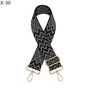 Close-up of geometric jacquard bag strap with gold metal hooks and adjustable slider